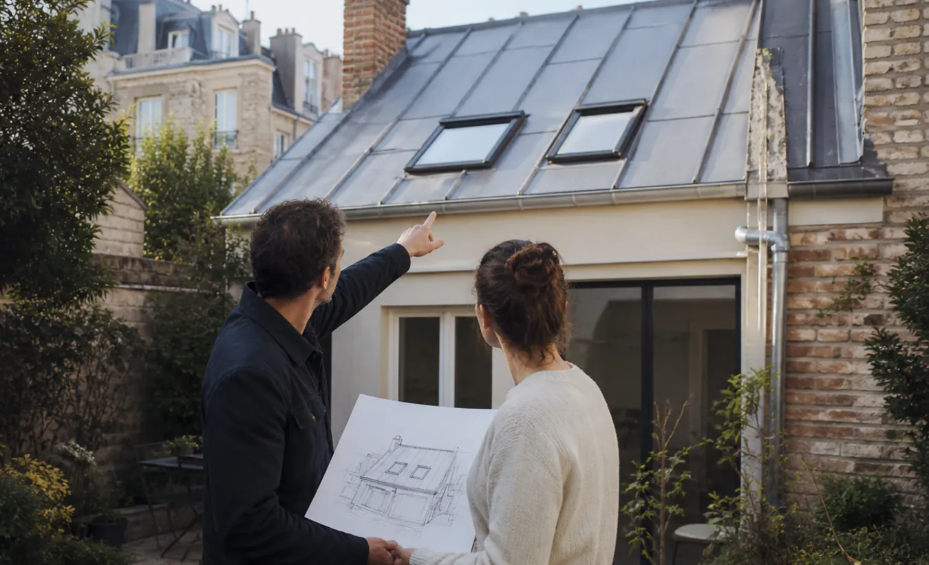 Un architecte et un propriétaire étudient deux fenêtres de toit sur une maison d'Île-de-France avec un jardin compact
