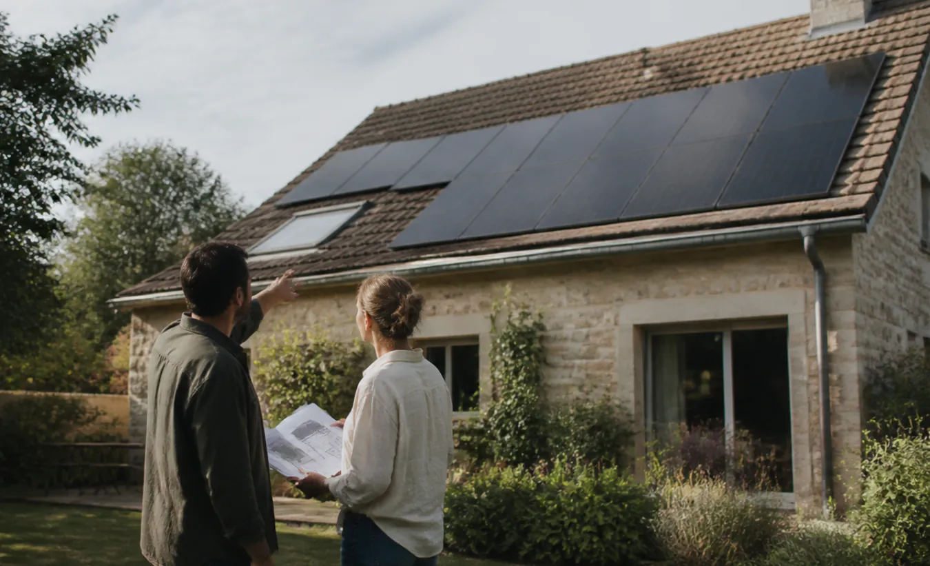 Un architecte et une propriétaire vérifient des panneaux solaires sur une maison de l'intérieur de la France en pierre et enduit clair